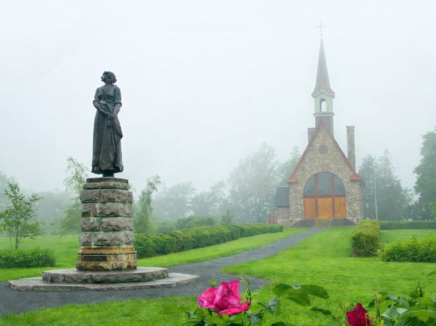 Statue of Evangeline at Grand Pré National Historic Site with memorial church in Nova Scotia