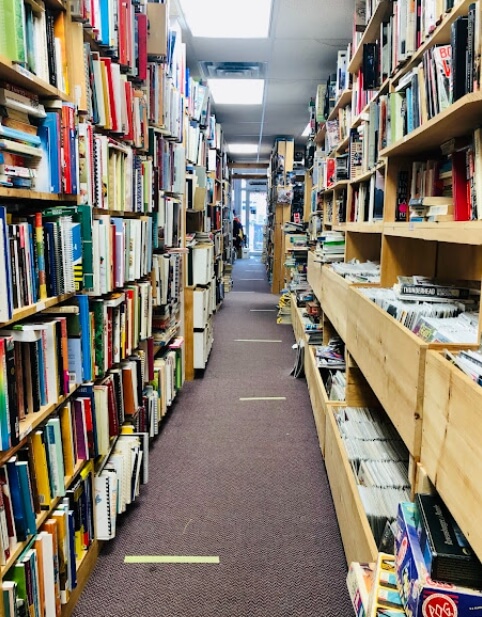 Narrow aisle filled with books inside Rainbow’s End Books and Discs in Wolfville, Nova Scotia
